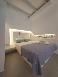a white bedroom with a bed with a blue blanket at Margaret's Houses in TINOS Town in Tinos