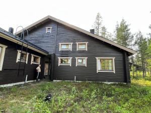 a man standing in front of a black house at Susitupa 5 in Salla