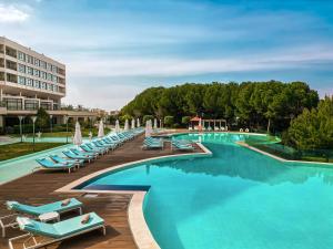 a pool with blue lounge chairs and a building at Kaya Izmir Thermal & Convention in Izmir