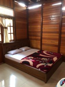 een slaapkamer met een bed in een kamer met houten wanden bij Roemah Kayu Saragan Syariah Magelang Mitra RedDoorz 