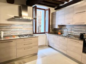 La cuisine est équipée de placards blancs et d'un four avec plaques de cuisson. dans l'établissement Franciosa Lodge - Cattedrale, à Sienne