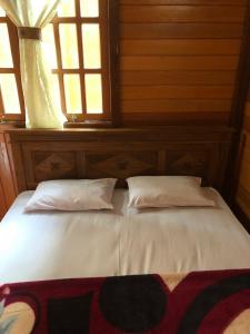 een bed met 2 kussens in een kamer met een raam bij Roemah Kayu Saragan Syariah Magelang Mitra RedDoorz 
