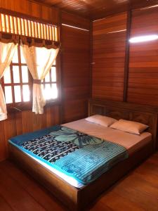 een bed in een kamer met houten wanden en een raam bij Roemah Kayu Saragan Syariah Magelang Mitra RedDoorz 