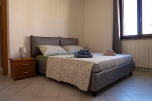 a bedroom with a bed and a night stand and a window at Casa Le corti in Livorno