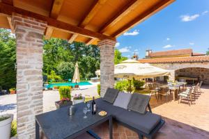 eine Terrasse mit einem Tisch, Stühlen und einem Sonnenschirm in der Unterkunft Villa Damiana in Petrići