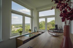 a room with windows and a table with a vase of flowers at Ferienwohnung Weitblick in Naumburg