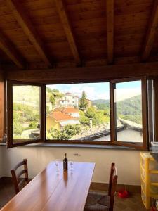 una mesa de madera con 2 copas de vino frente a una ventana en La delizia della valle, 