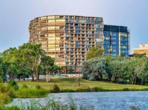 a large apartment building next to a body of water at Nishi Holiday Apartments in Canberra