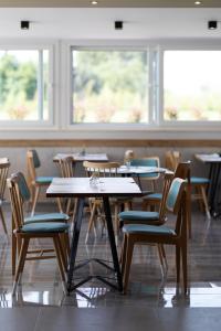 un comedor con mesas, sillas y ventanas en Mythic Summer Hotel en Paralia Katerinis