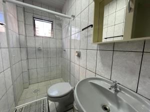 La salle de bains blanche est pourvue d'un lavabo et de toilettes. dans l'établissement Aconchegante apartamento no centro em Balneário Camboriú SC, à Balneário Camboriú