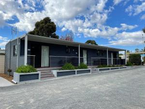 une maison noire avec terrasse couverte dans une rue dans l'établissement Acacia Caravan Park & Holiday Units, à Ararat