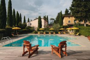 uma piscina com duas cadeiras e guarda-sóis em Villa La Cappella em Montespertoli