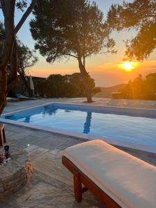 a swimming pool with a bench in front of a sunset at Villa Art Natalie in Kithnos