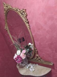 a mirror with a vase of flowers on a chair at La Peonia in Vitorchiano