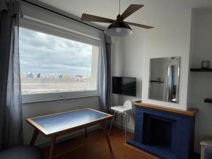 a living room with a fireplace and a large window at l'albatros "le pont" in Cayeux-sur-Mer