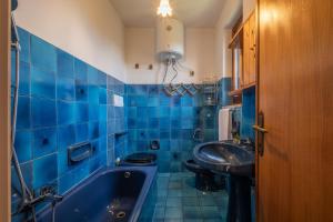 baño de azulejos azules con bañera y lavamanos en [5 Min Budoni]Terrazzo Vista Borgo & Self Check-In, en Tanaunella