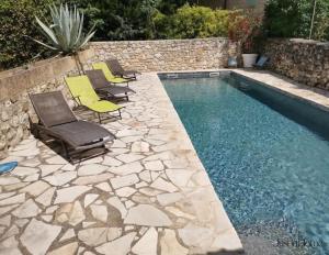 a swimming pool with chairs and a rock wall at Mas en pierre de 300m2, piscine, terrasse, 4 chbre in Sainte Anastasie - Aubarne