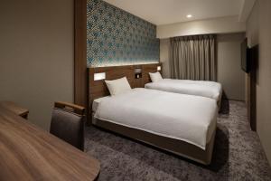 a hotel room with two beds and a tv at the b namba-kuromon in Osaka