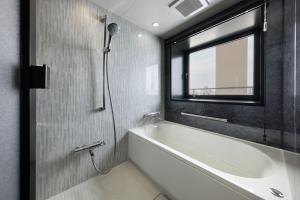 a bathroom with a bath tub and a window at the b namba-kuromon in Osaka