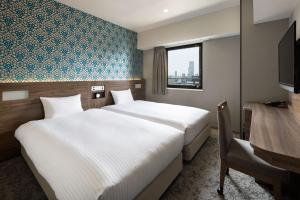 a hotel room with two beds and a window at the b namba-kuromon in Osaka