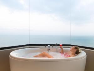 a girl laying in a bath tub with a glass of wine at Cape Dara Resort - SHA Plus in North Pattaya