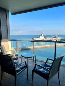 a balcony with chairs and a table and a view of a ship at Sea Renity at Waterfront - SEAVIEW in Darwin