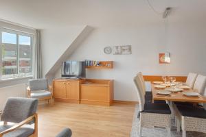 a living room with a table and chairs and a television at Apartment 11 - Maisonette in Heiligenhafen