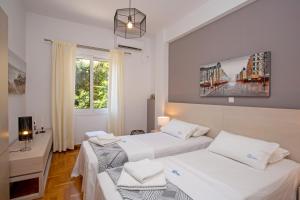 two beds in a room with two windows at Hadrian by Heloni Apartments in Athens