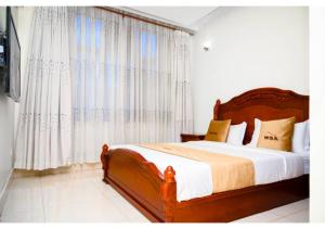 1 dormitorio con 1 cama grande y cortinas blancas en White Stone Apartments, en Kigali