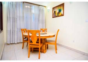 uma sala de jantar com uma mesa de madeira e cadeiras em White Stone Apartments em Kigali
