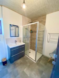 ein Bad mit einer Dusche und einem Waschbecken in der Unterkunft Maison Calme avec extérieur 