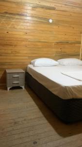 1 dormitorio con 2 camas y pared de madera en Pina bungalov restaurant, en Ayvacık