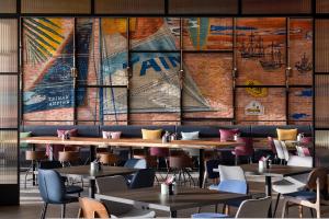 a restaurant with tables and chairs and a large mural at Aloft by Marriott Tainan Anping in Tainan