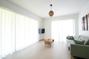 una sala de estar con paredes blancas y ventanas grandes. en Ennea suites-Earth suite, en Flámbouras