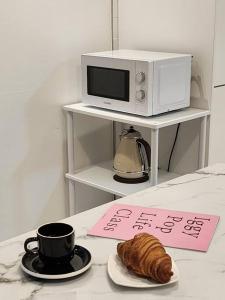 a table with a cup of coffee and a croissant and a microwave at Dawn House in Seoul