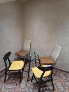 einen Glastisch mit drei Stühlen, einem Glastisch und zwei Stühlen in der Unterkunft Departamento Aeropuerto CDMX in Mexiko-Stadt