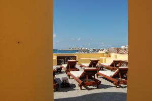 a row of chaise lounges on a balcony with the beach at El Mosaico Del Sol in Lampedusa