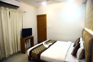 a bedroom with a bed and a television in it at Pine Tree Signature in Chennai