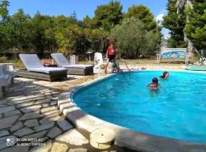 a swimming pool with two people in the water at Villa w Studio, Pool, Garden, Sleeps 12 to 15 in Rákhai