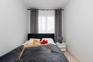 una camera da letto con un letto e un vassoio di cibo sopra di Sunny Apartments with Parking & Balcony Łużycka by Renters a Świnoujście