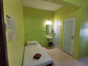 a green bathroom with a bed and a sink at Walk Inn in Miri