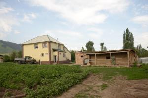 een huis en een schuur en een truck in een veld bij Woody Guest House Nursultan in Kaindy
