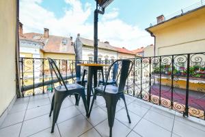 a balcony with two chairs and an umbrella at My Place Ferdinand in Cluj-Napoca