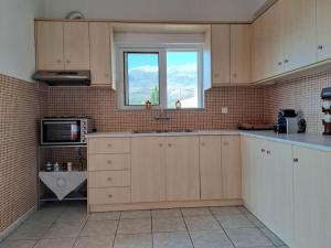 a kitchen with white cabinets and a window at Fully equipped apartment in Apokoronas in Nípos