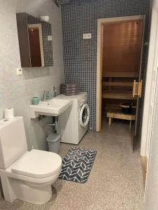 Cozy Sauna Apartment في بارنو: حمام مع حوض استحمام وغسالة ملابس