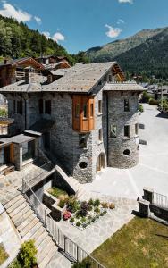 a large stone house with a roof at Grey Castle garnì&suite in Ponte di Legno