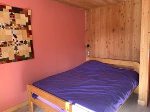 een kleine slaapkamer met een bed met paarse lakens bij Les Astrances, logement dans une maison de village in Huez