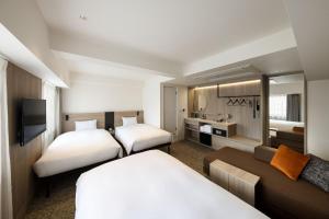 a hotel room with two beds and a couch at the b namba-kuromon in Osaka