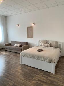 een witte slaapkamer met een bed en een bank bij Somogyi Béla Apartments in Boedapest