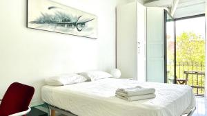 a white bedroom with a bed and a red chair at Enric Granados 17 in Barcelona